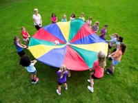 Teacher and students bouncing a ball on a parachute