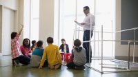 A teacher and a group of students discuss an inquiry-based project.