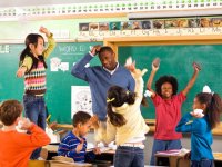 Male teacher scratching his head surrounded by students having a balled up paper fight