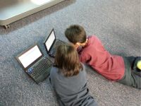 A photo of 2 elementary-school boys doing research on laptops.