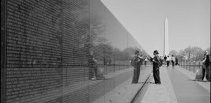 Black and white photo of a girl at the War Memorial with her hand touching one of the names