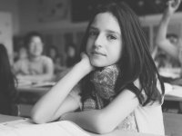 black and white photo of a student at a desk looking at the camera