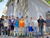 11 boys standing in front of a two-story house they have been renovating