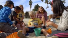 A group of fourth-grade students play with a peer with special needs in a sandbox during a field trip to a local playground in southern California. 