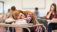 A bored student sleeps at her desk.