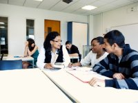 Teacher speaking with two older students at a table