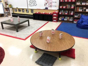 Two low-seated tables coupled with rugs and floor pillows in a classroom