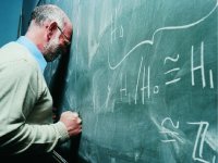 Man with his forehead and fist against a blackboard