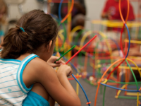 A photo of an elementary-school girl creating a model with colorful sticks.