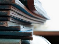A closeup of a stack of blue, old, faded books on a circular table.