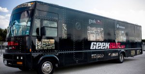 A close-up exterior shot of a large black-painted RV that says Geekbus in large lettering. 