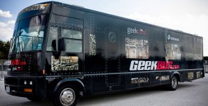 A close-up exterior shot of a large black-painted RV that says Geekbus in large lettering.