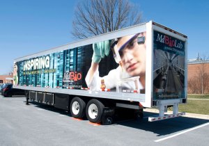 The exterior of a semi-truck with a picture of a boy in a lab coat wearing protective glasses and gloves.