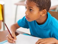 Boy looking up, writing with pencil