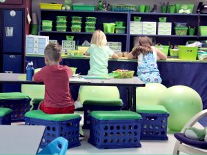 Students are sitting on yoga balls and crate chairs in a classroom.