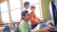 three boys looking at computers