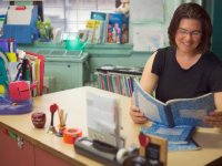 Teacher sitting at her desk reading from a student composition book