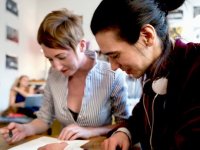 Two women at desk looking at papers together