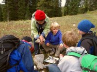 Five children bundled up in a forest identifying rocks