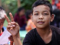 A closeup of a young boy giving the peace sign with his fingers. 