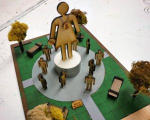 A model of a monument in a public square with grass and trees