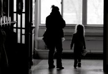 An adult woman and a young girl are walking down a school hallway. 