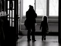 An adult woman and a young girl are walking down a school hallway. 