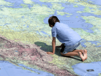 A photo of a young boy kneeling on a giant map of the world.