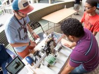 Man and boy visiting a work station with laptop and circuit boards