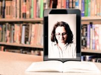 A photo of a photograph on a tablet propped up on a book. The tablet image shows a woman looking down at the book.