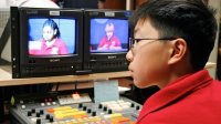 Boy at monitors and mixing board for school broadcast