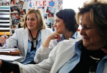 Three women all wearing white coats sitting in discussion