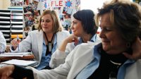 Three women all wearing white coats sitting in discussion