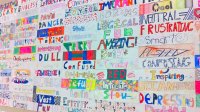 A school bulletin board covered with many hand-decorated words students used to describe school, including "fun," "confusing," "boring," and "important"