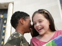 Boy whispering into a girl's ear both smiling