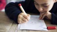 A young student does classwork in pen.