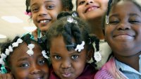 Five young girls huddled together cheek-to-cheek smiling