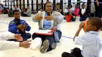 Teacher sitting on floor with students playing ball