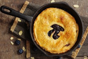 A blueberry pie in a skillet with the mathematical pi symbol cut into the top
