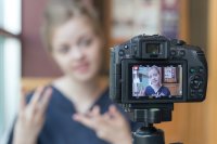 A student filming herself talking on a DSLR camera