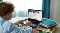 Teenage boy at desk attending online class. 