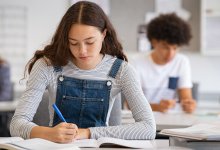 High school student writing in classroom