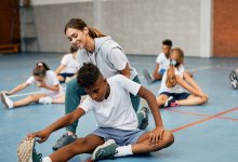 Middle school student stretches with teacher in gym class