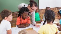 Elementary school teacher helps students in classroom