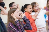 A class of elementary drama students make a variety of pronounced expressions