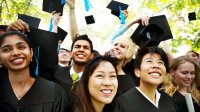 A diverse group of high school graduates throwing their graduation caps into the air at an outdoor graduation ceremony