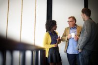 Two teachers talking to an administrator in the hallway of a school