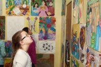 A middle school student attending a student art show, looking at her classmates' art on the wall