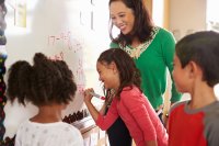 Teacher helping group of students with a math problem