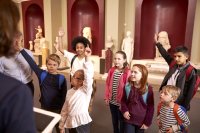 Group of students raising their hands during a museum field trip.